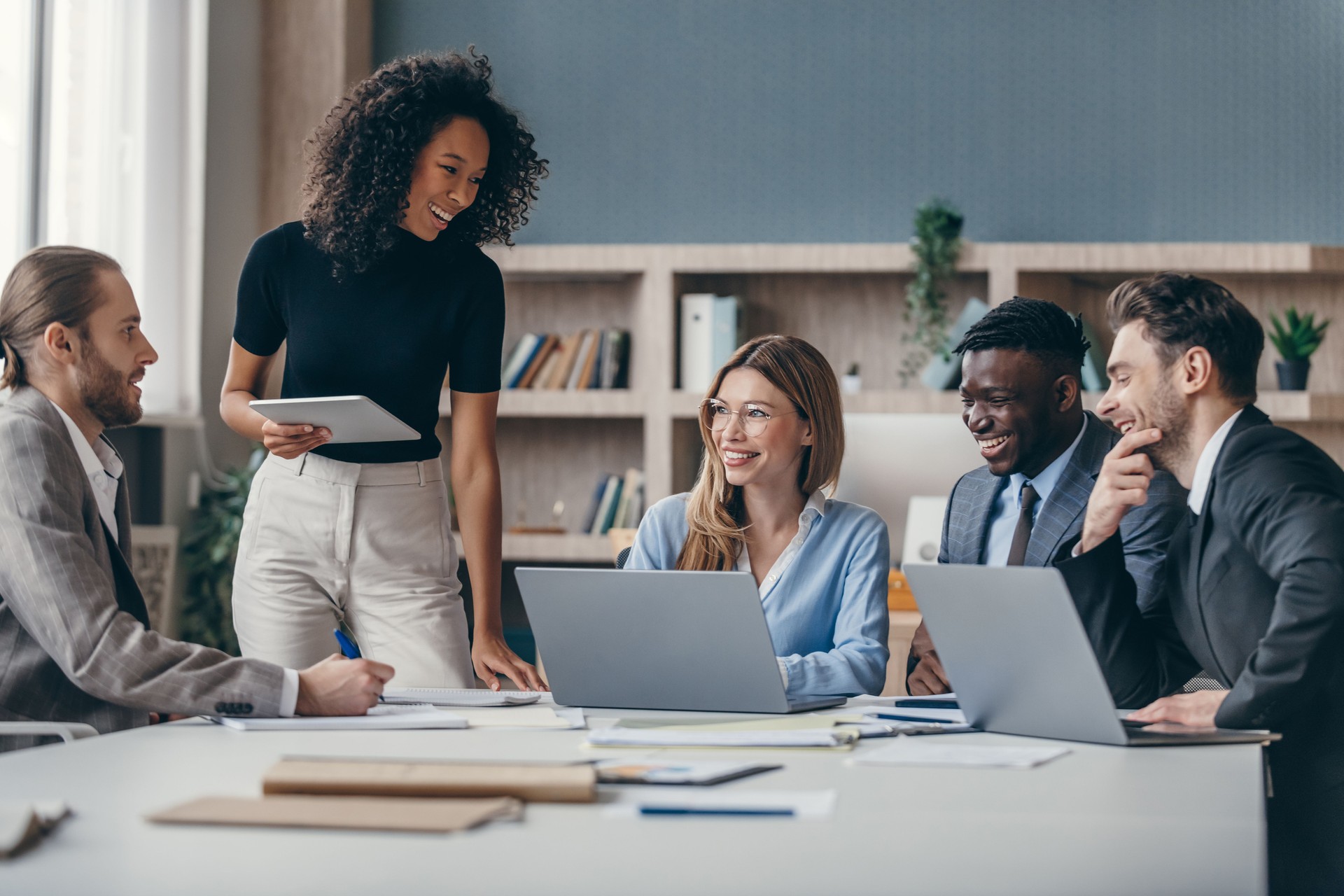 Happy group of business people discussing strategy during team meeting at the office desk together Happy group of business people discussing strategy during team meeting at the office desk together